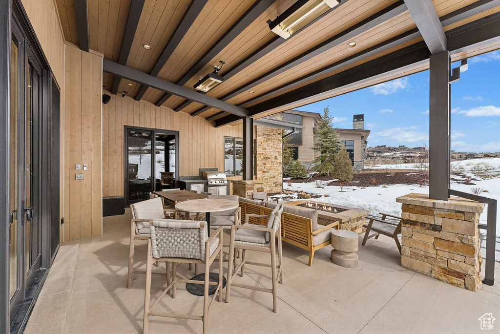 Snow covered patio featuring outdoor dining space, a fire pit, and area for grilling