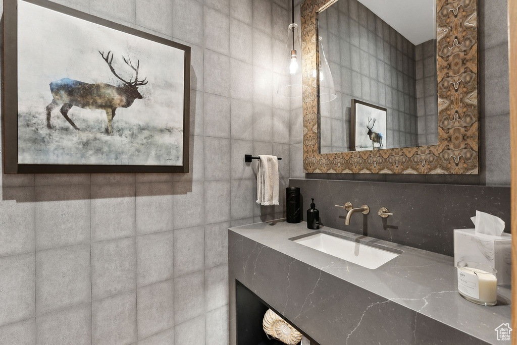 Bathroom featuring backsplash, tile walls, and a sink