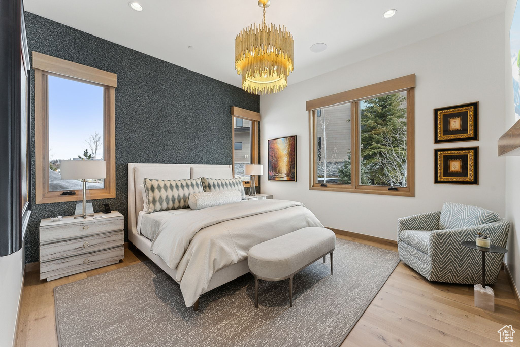 Bedroom featuring multiple windows, wood finished floors, and wallpapered walls