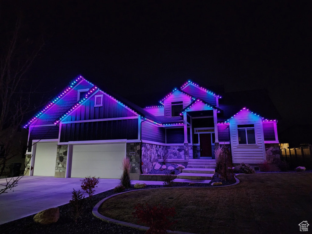View of front of home featuring stone siding, driveway, and board and batten siding