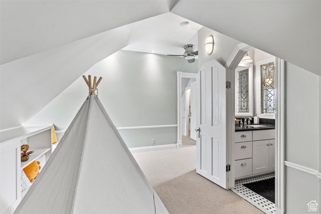Hall featuring light carpet, vaulted ceiling, and a sink