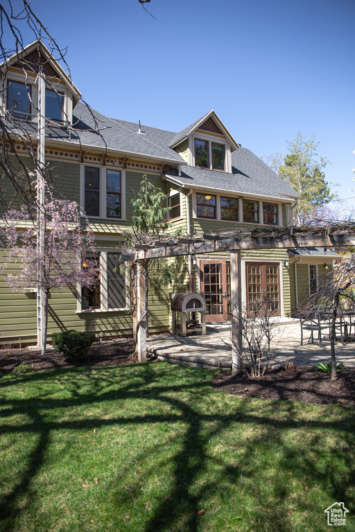 Back of house with a yard, a patio, and roof with shingles