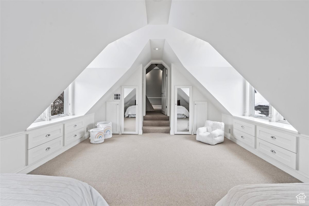 Bedroom featuring multiple windows, carpet, and lofted ceiling