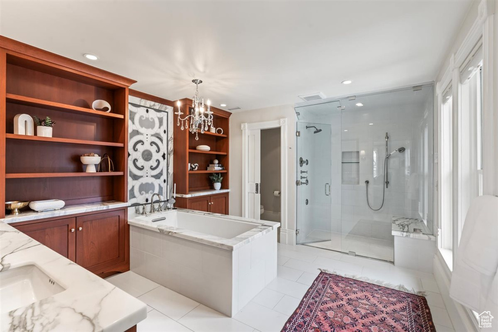 Bathroom featuring a chandelier, toilet, a stall shower, a bath, and vanity