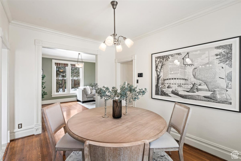 Dining room featuring dark wood-type flooring, a chandelier, and ornamental molding