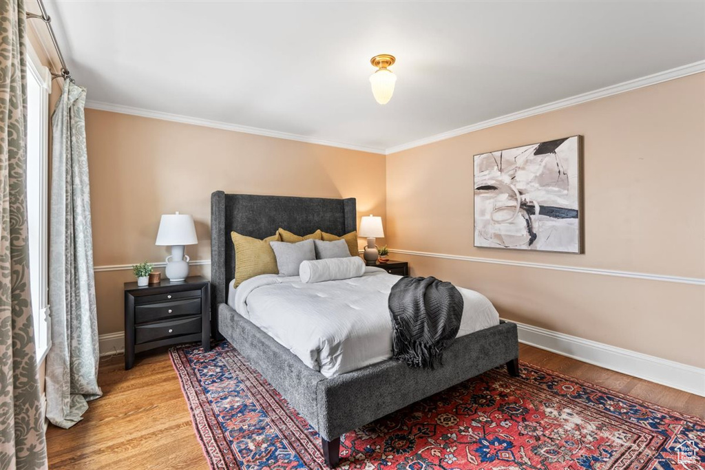 Bedroom with wood finished floors, baseboards, and ornamental molding