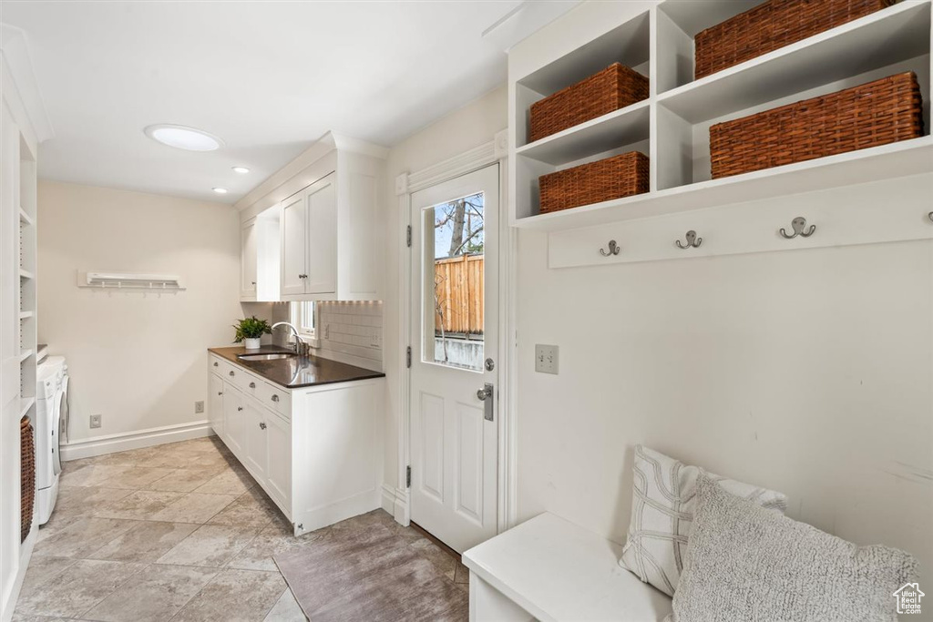 Mudroom featuring washer and dryer, baseboards, and a sink