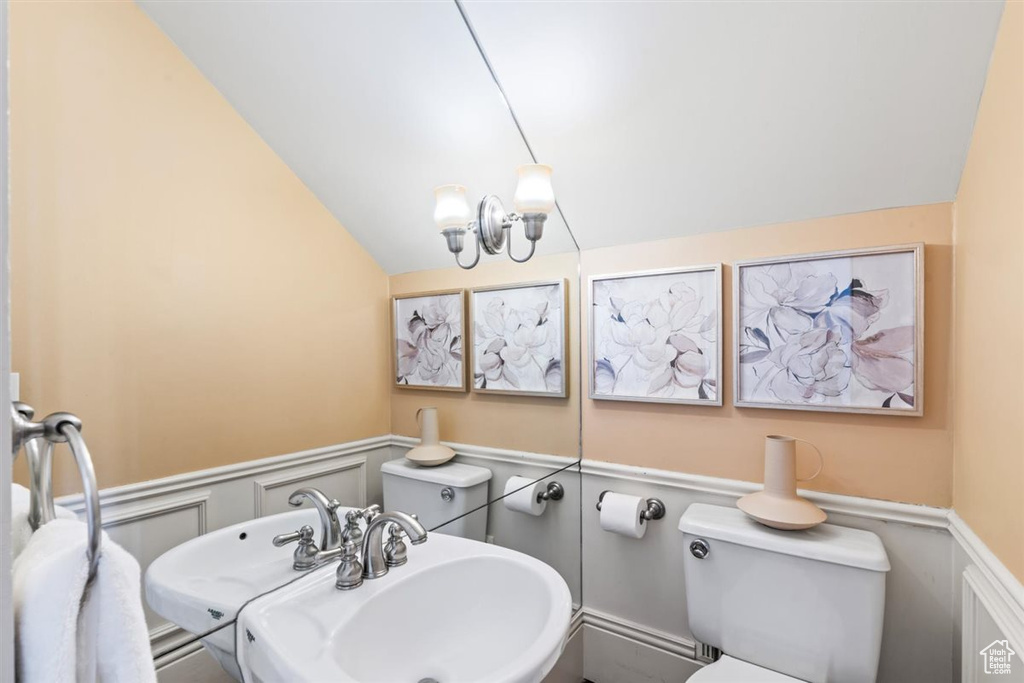 Bathroom with a sink, a wainscoted wall, toilet, and vaulted ceiling