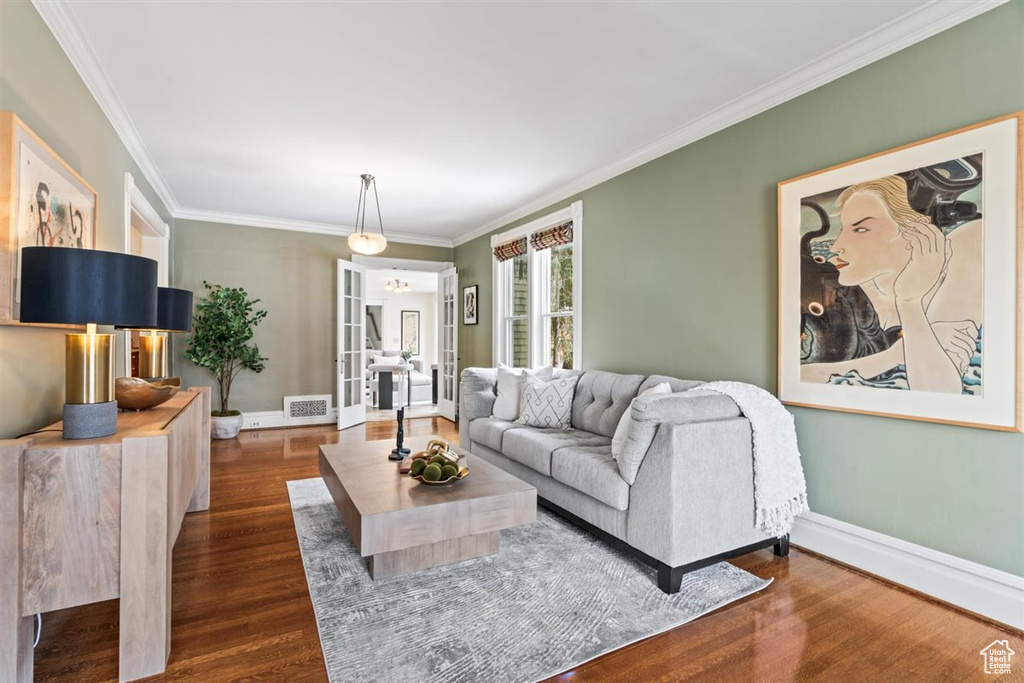 Living area featuring visible vents, baseboards, dark wood-style flooring, and crown molding