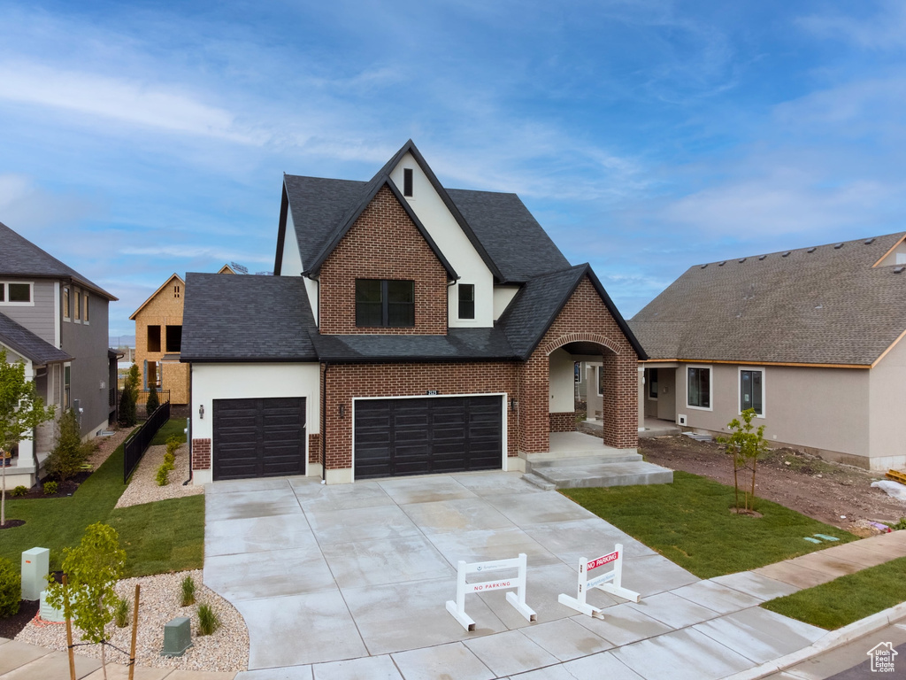 View of front of house with concrete driveway, brick siding, a front yard, and roof with shingles