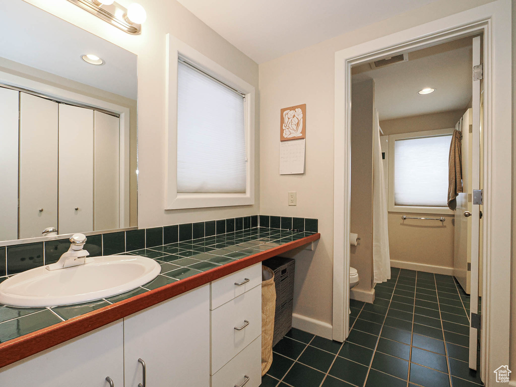 Full bathroom with vanity, baseboards, recessed lighting, tile patterned flooring, and toilet