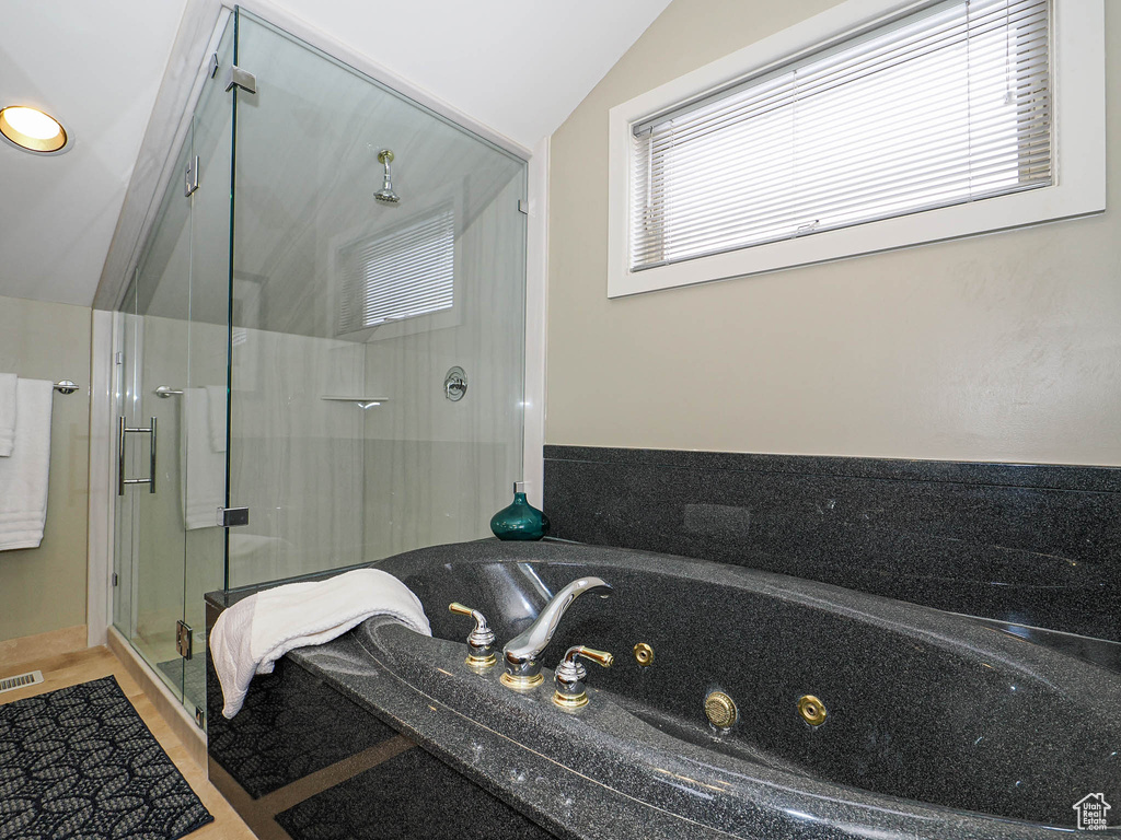 Full bath with visible vents, lofted ceiling, a tub with jets, and a shower stall