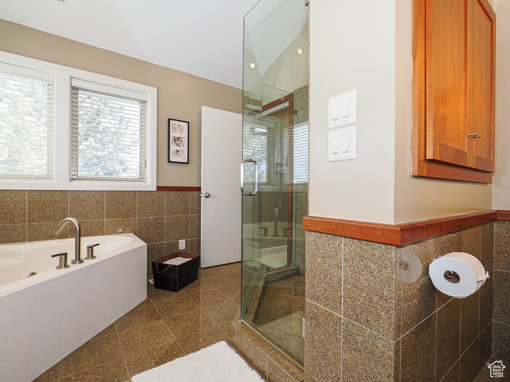 Bathroom with a garden tub, a wainscoted wall, granite finish floor, a shower stall, and tile walls