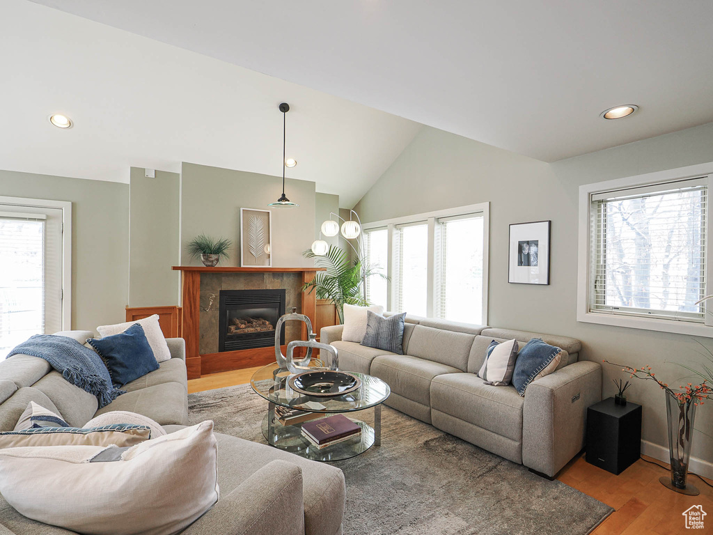 Living area featuring a tiled fireplace, wood finished floors, recessed lighting, baseboards, and vaulted ceiling