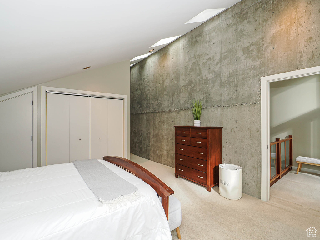 Bedroom featuring vaulted ceiling, a closet, and light carpet