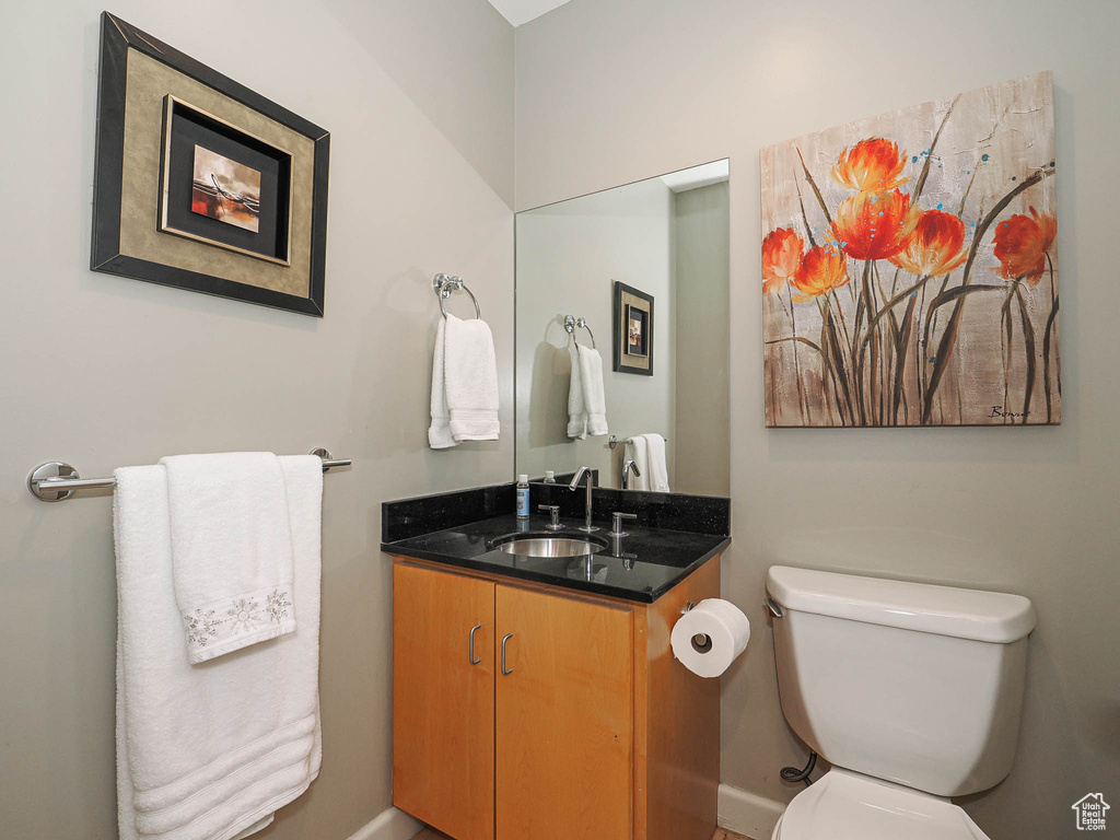 Bathroom featuring vanity, toilet, and baseboards