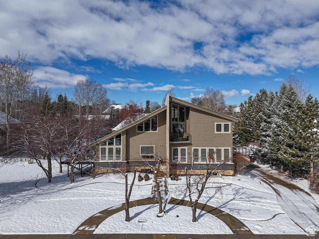 Snow covered rear of property featuring a balcony