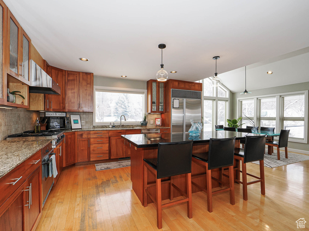 Kitchen with range hood, a kitchen breakfast bar, plenty of natural light, and appliances with stainless steel finishes