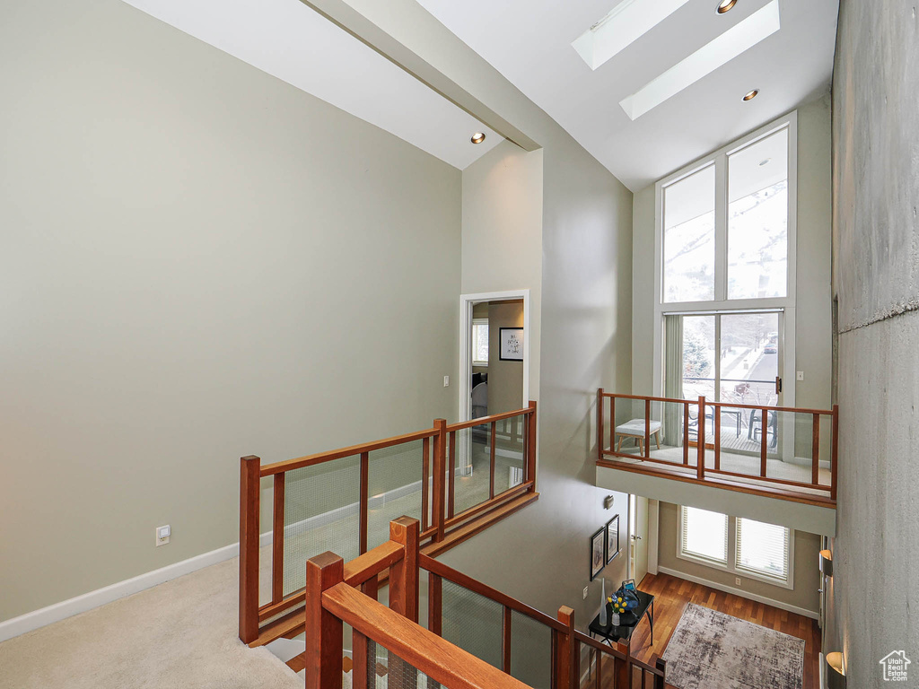 Stairway featuring lofted ceiling with skylight, recessed lighting, a healthy amount of sunlight, and baseboards