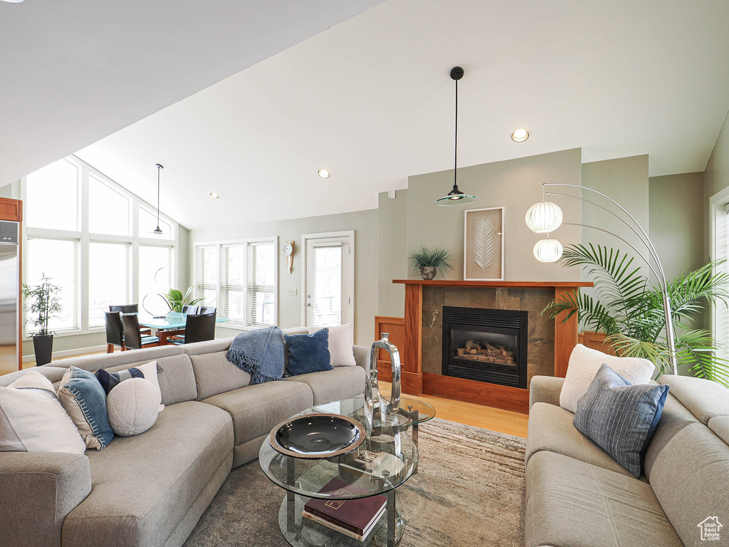 Living room featuring a glass covered fireplace, recessed lighting, wood finished floors, and vaulted ceiling