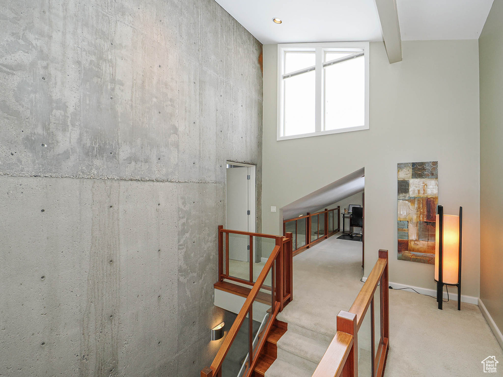 Stairway with beam ceiling, baseboards, a towering ceiling, and carpet floors