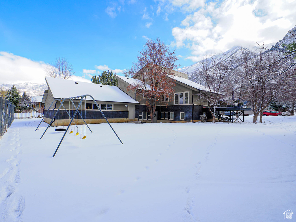 Snow covered back of property featuring fence and a mountain view