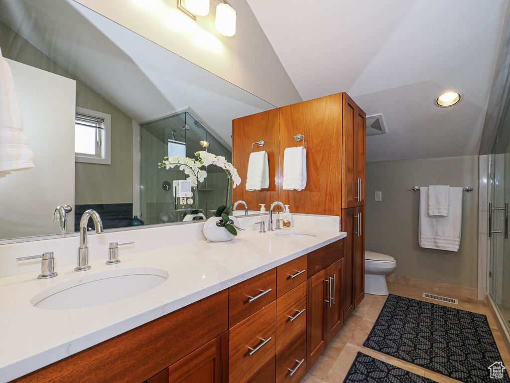 Full bath with vaulted ceiling, visible vents, double vanity, and a sink