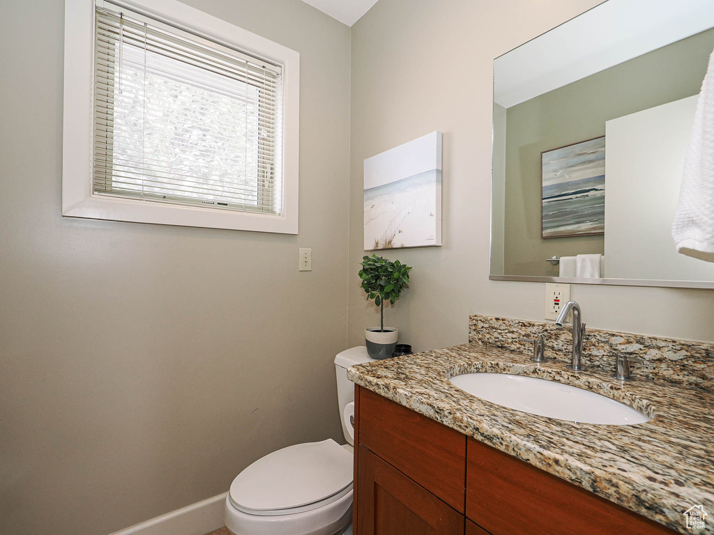 Bathroom featuring vanity, toilet, and baseboards