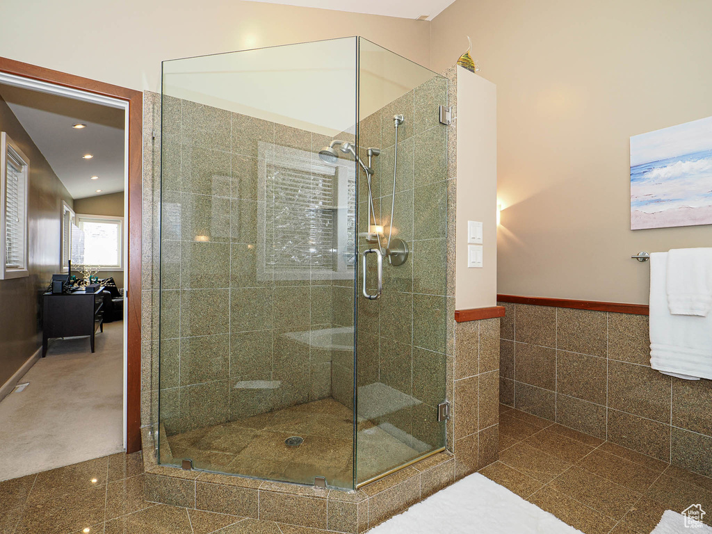 Bathroom featuring tile walls, recessed lighting, a stall shower, and wainscoting