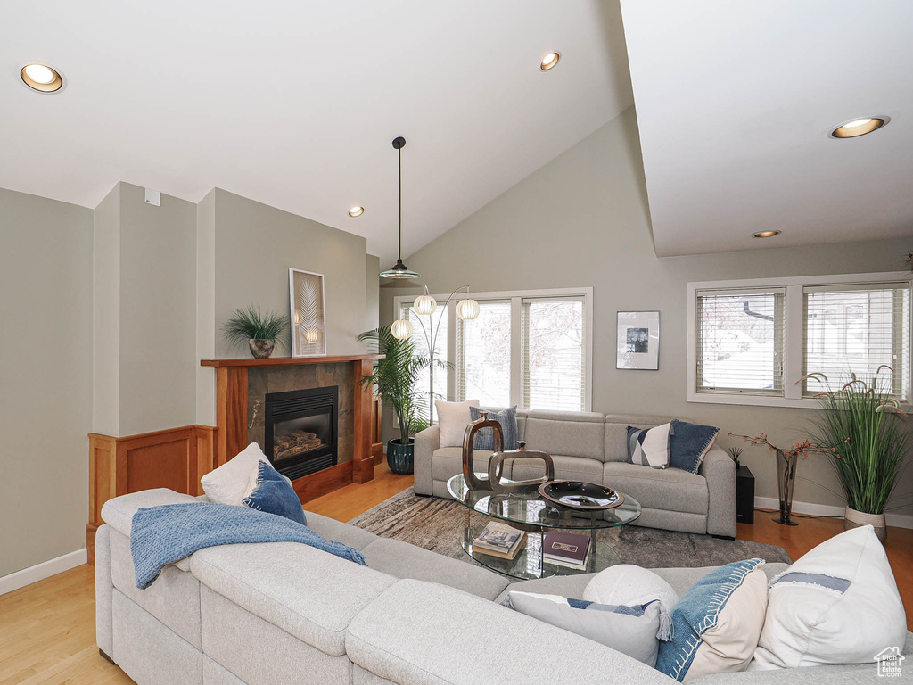 Living room with light wood finished floors, baseboards, recessed lighting, a fireplace, and high vaulted ceiling