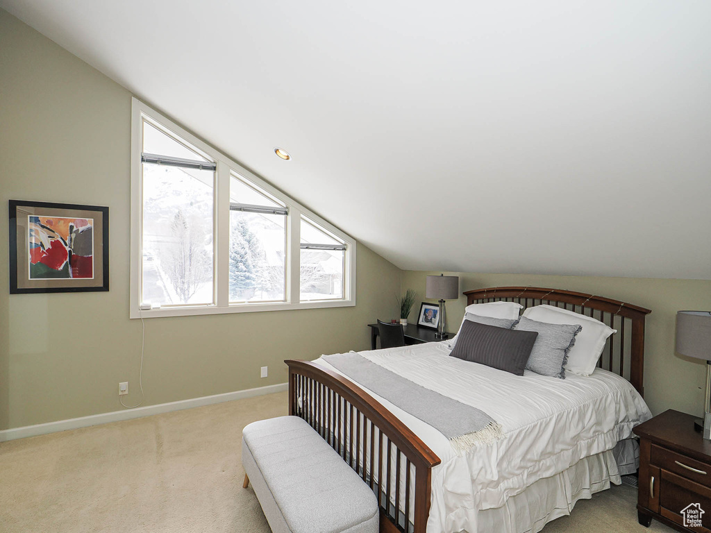 Bedroom featuring baseboards, light colored carpet, and vaulted ceiling