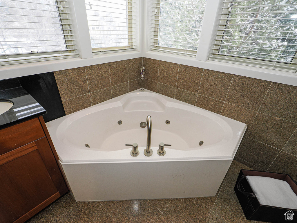 Bathroom with a jetted tub, granite finish floor, and a wealth of natural light