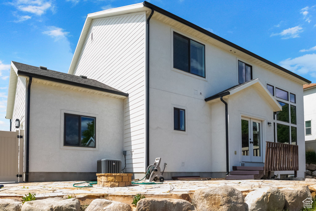 Back of property with french doors, central air condition unit, and stucco siding