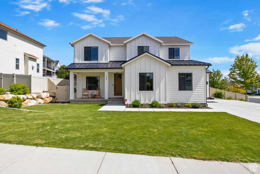 Modern farmhouse featuring board and batten siding, a standing seam roof, a porch, and metal roof