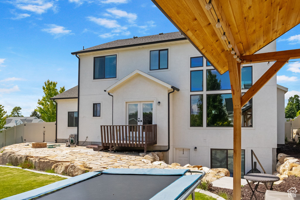Back of house with french doors, stucco siding, a patio area, and roof with shingles