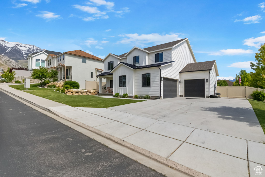 View of front of property with board and batten siding, concrete driveway, a mountain view, and an attached garage