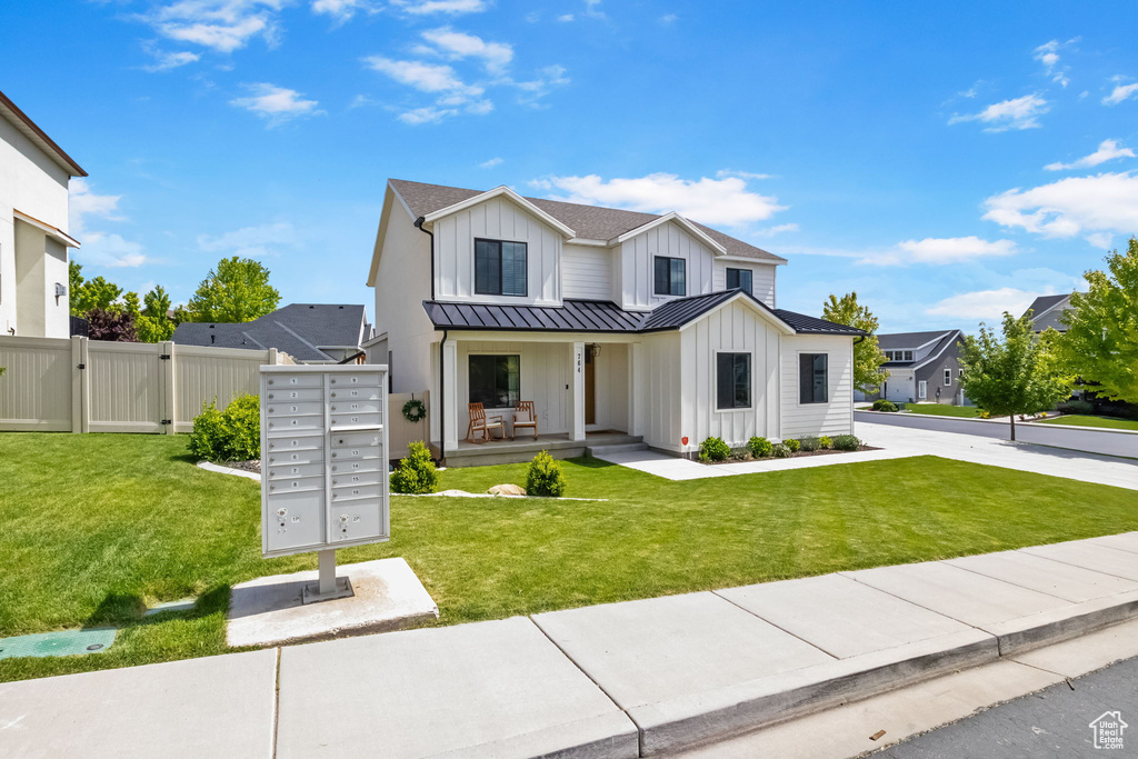 Modern inspired farmhouse featuring board and batten siding, a standing seam roof, metal roof, and a front lawn