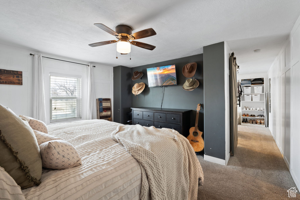 Bedroom with a textured ceiling, a ceiling fan, baseboards, and light carpet