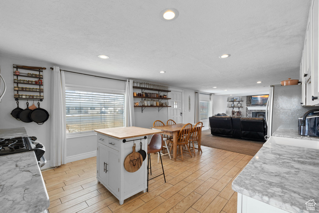 Kitchen with light wood-type flooring, a kitchen bar, white cabinets, and freestanding refrigerator
