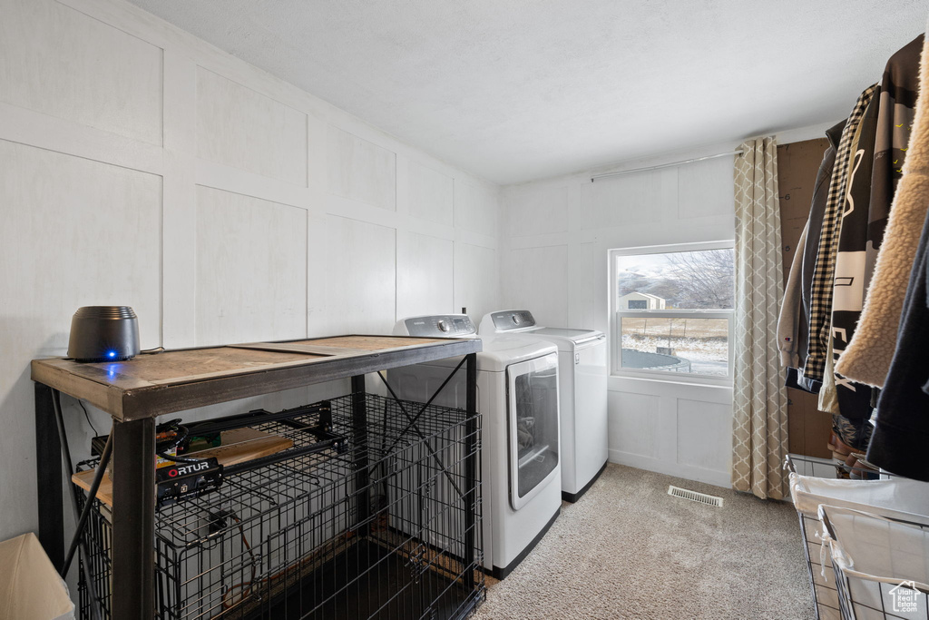 Laundry room with visible vents, light carpet, laundry area, a decorative wall, and independent washer and dryer