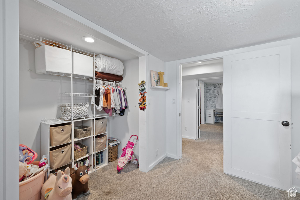 Interior space with a textured ceiling, recessed lighting, a closet, baseboards, and light colored carpet