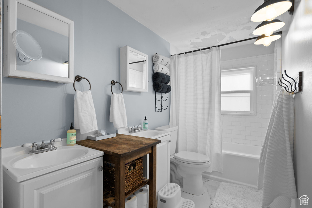 Full bathroom featuring marble finish floor, vanity, shower / tub combo with curtain, and toilet