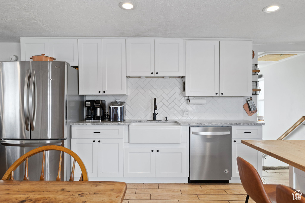 Kitchen featuring a sink, white cabinets, and stainless steel appliances