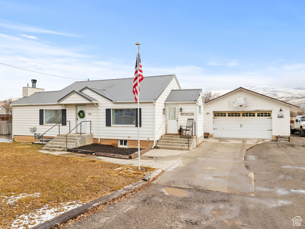 Ranch-style home featuring a chimney, driveway, and metal roof