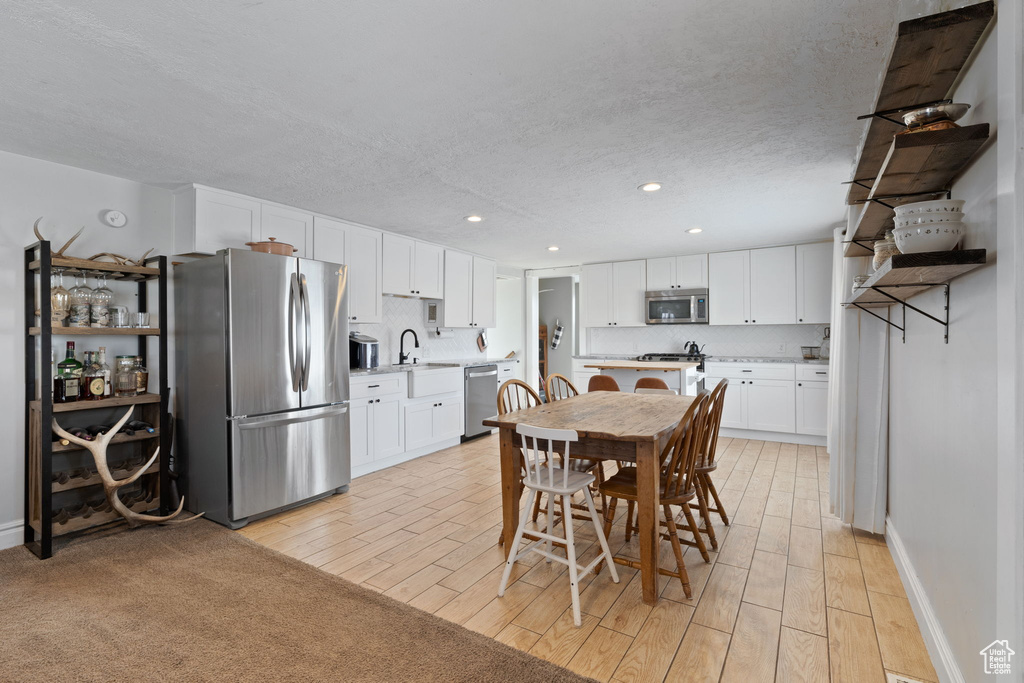 Dining area featuring recessed lighting, light wood-type flooring, baseboards, and a textured ceiling