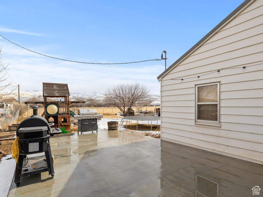 View of patio with fence, a trampoline, area for grilling, and a playground