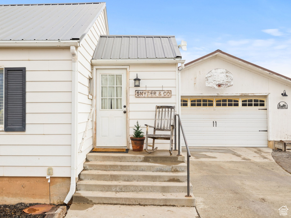 View of exterior entry with concrete driveway and metal roof