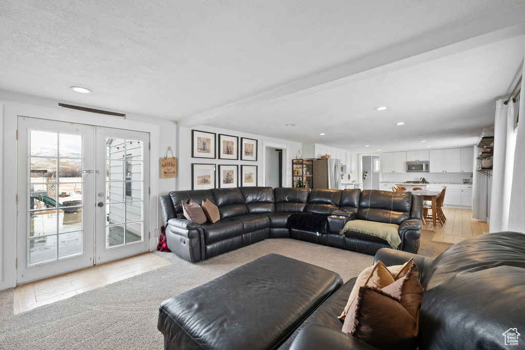 Living area featuring light colored carpet, light tile patterned floors, recessed lighting, french doors, and a textured ceiling