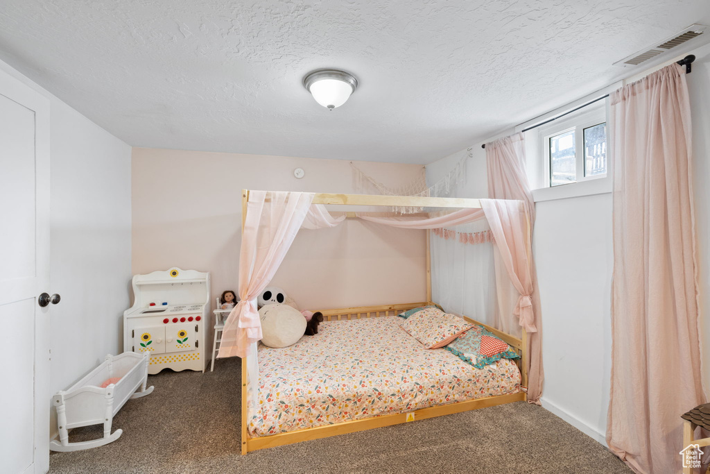 Bedroom featuring carpet flooring, visible vents, and a textured ceiling