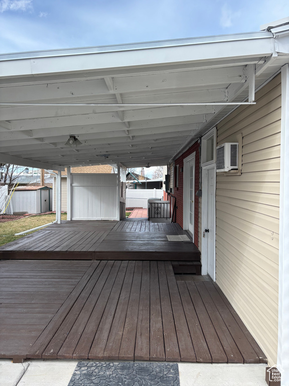 Wooden deck featuring an outbuilding, a wall mounted AC, and a storage shed